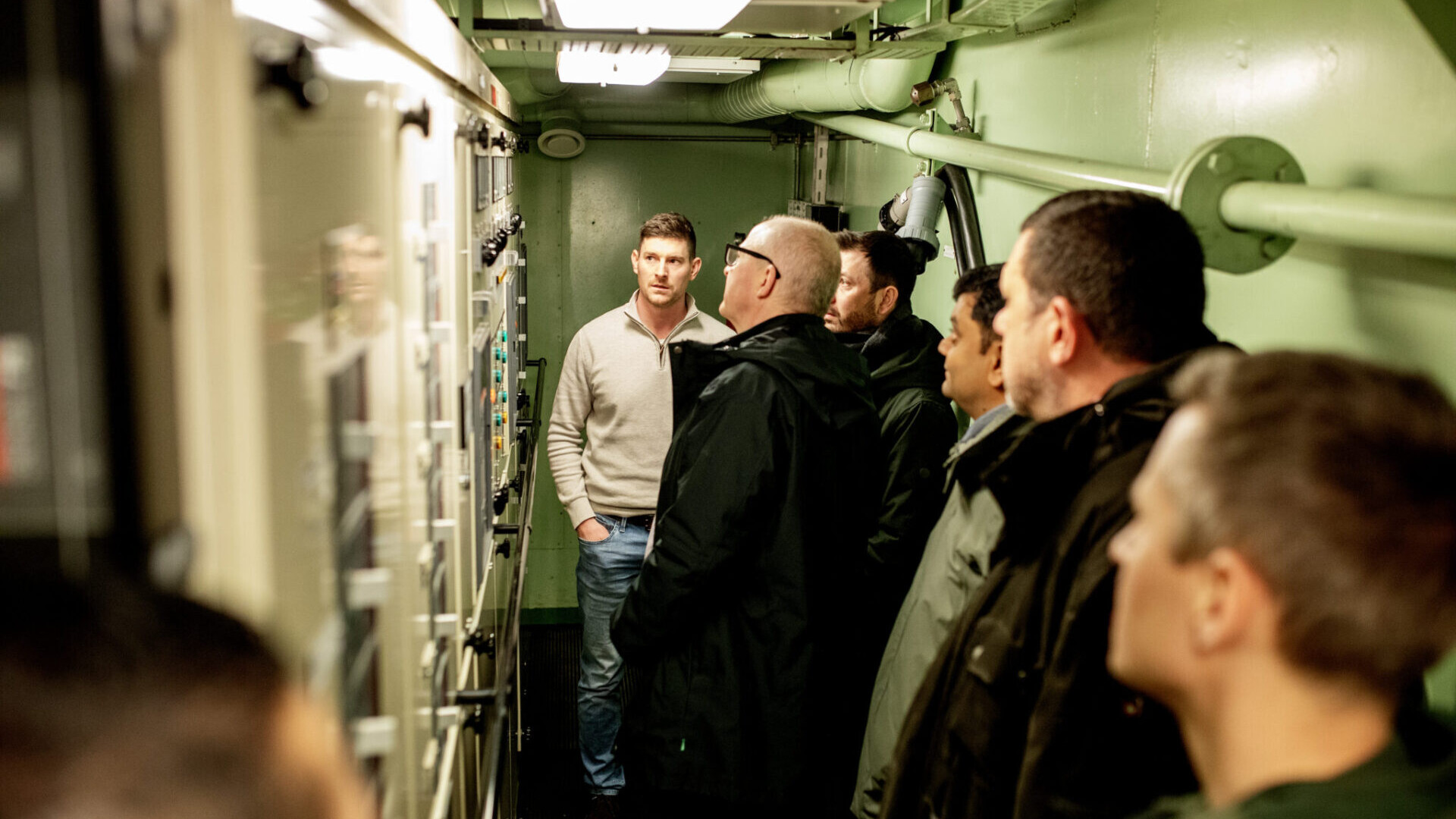 Maritime experts visiting a vessel engine control room.