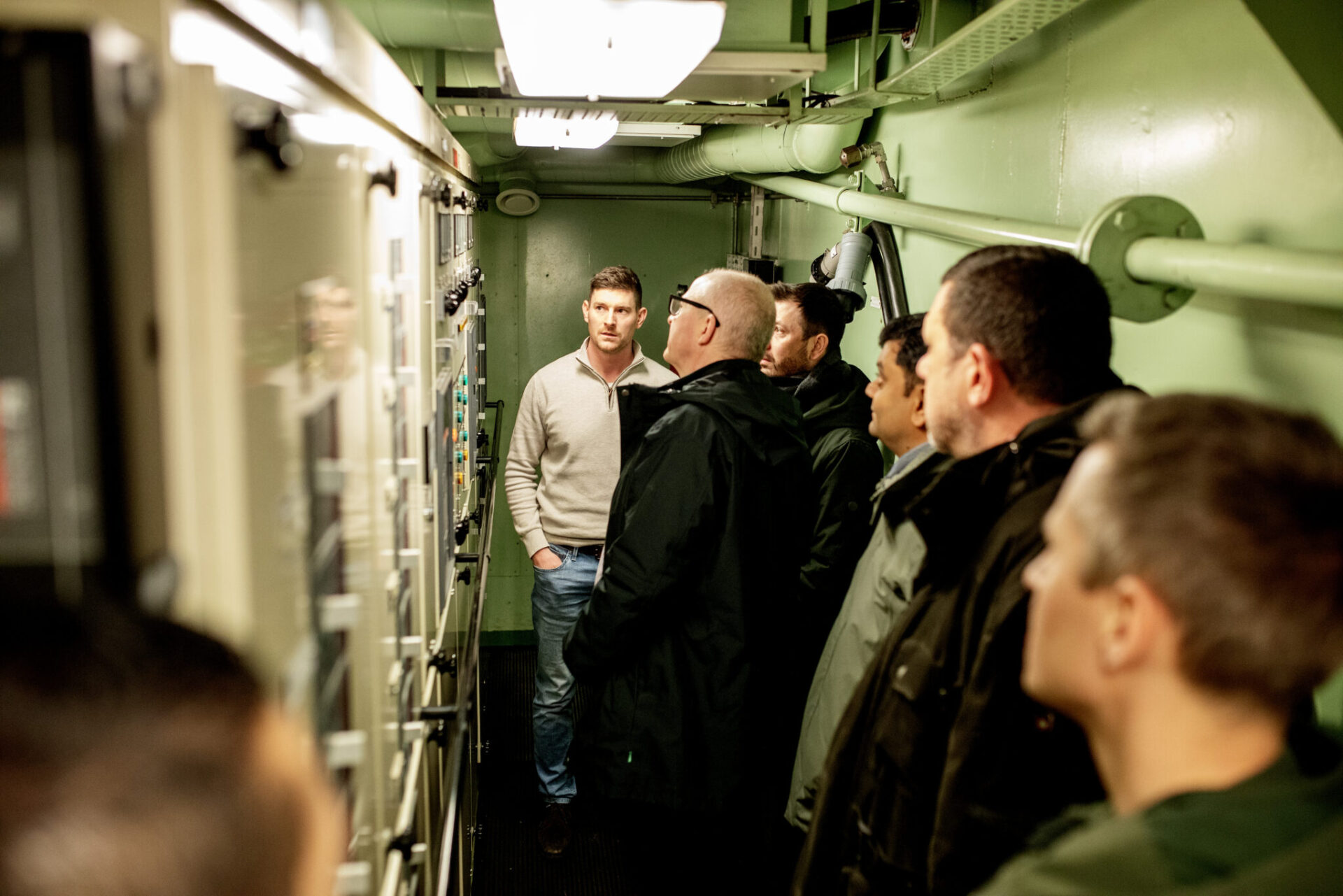 Maritime experts visiting a vessel engine control room.